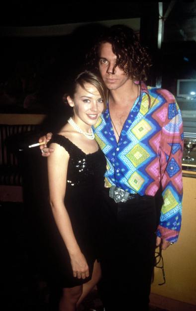 Pop stars Kylie Minogue and Michael Hutchence at an event, with Minogue holding a cigarette.