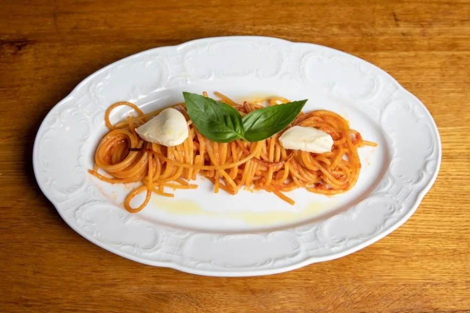 A plate of spaghetti all'assassina topped with mozzarella and basil.