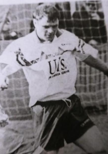 Black and white photo of a man in a soccer uniform, Franny Ventre, on a field with a goal net in the background.