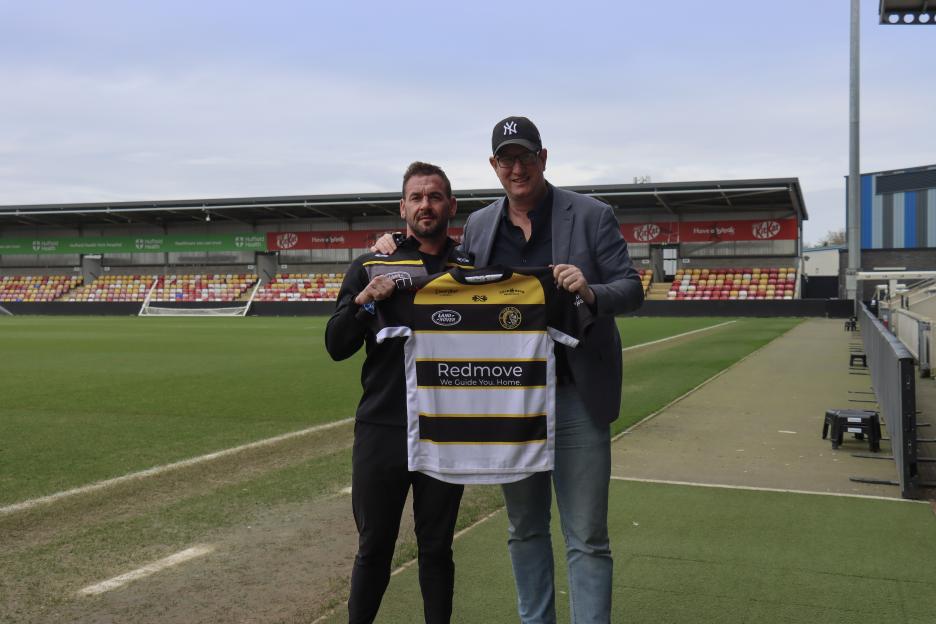 York chairman Clint Goodchild and another man hold up a team jersey on a sports field.