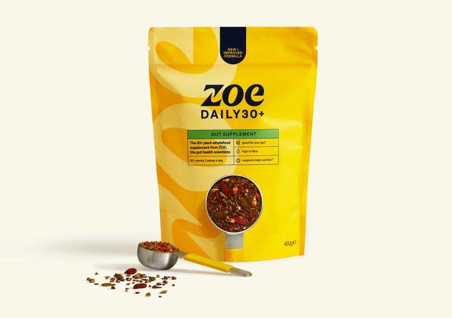 A yellow pouch of Zoe Daily 30+ Gut Supplement with a small metal scoop full of the supplement in front of it.