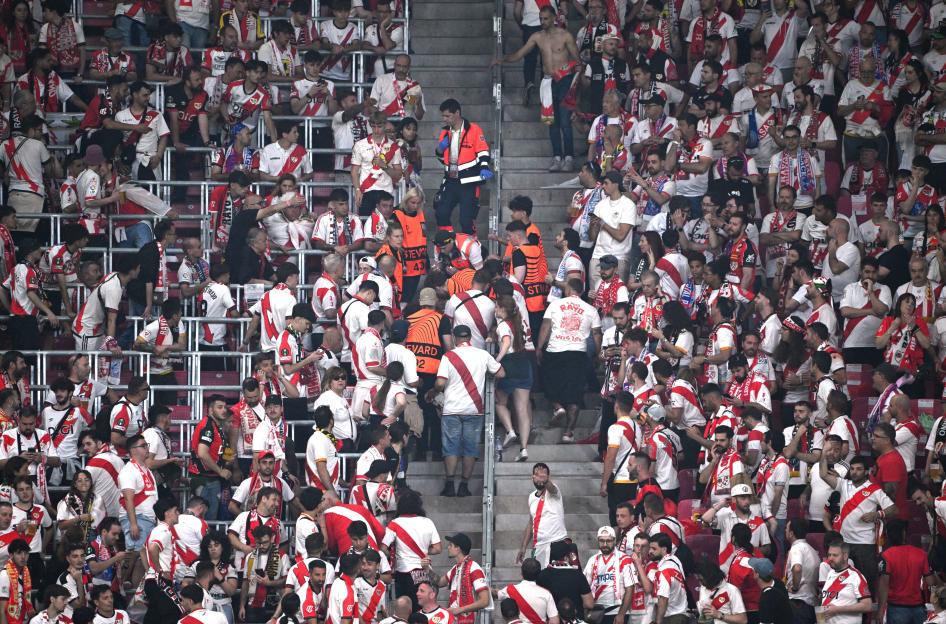 Crowd of fans in a stadium, many wearing red and white, with a scoreboard in the upper left corner showing "CRY 0 0 RAY" and a time of 36:57.