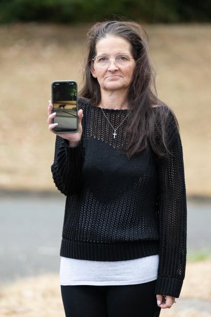 Clare Hodges holding up her phone displaying an image of a suspected big cat.