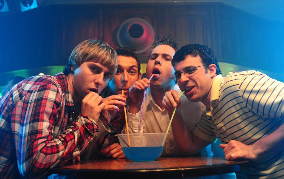 Four young men drinking from a blue bowl with straws.