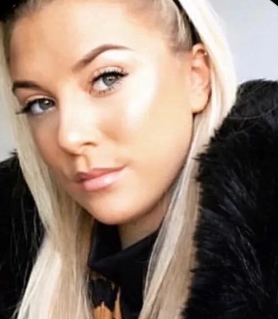 A woman with blonde hair, wearing a black fur coat.