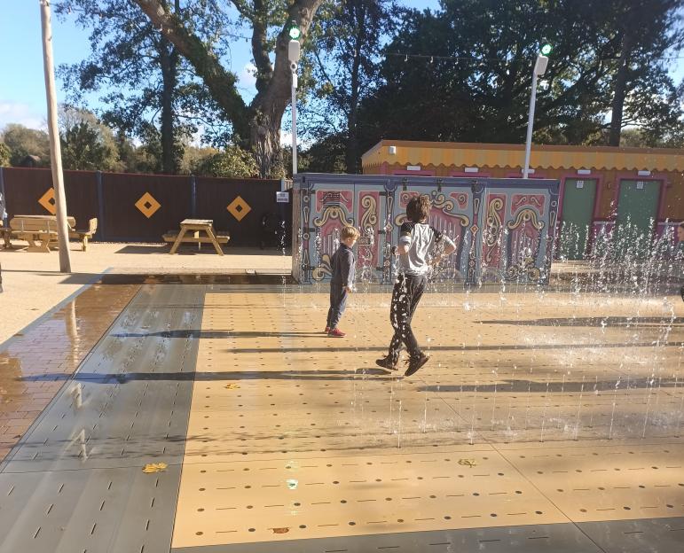 Two children playing in a funfair-themed splash pad.