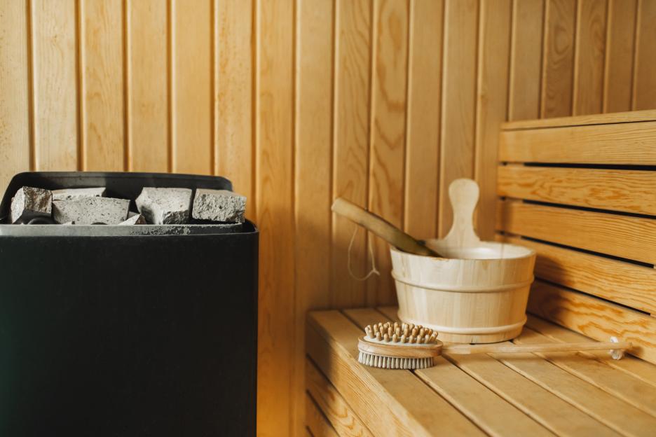 Background of finnish sauna with wooden bucket, stone heater, natural massaging brush