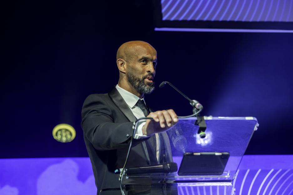 Leeds CEO Jamie Jones-Buchanan speaks at a podium.