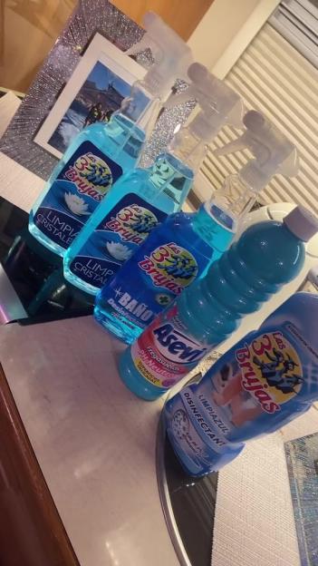 A collection of blue-colored Spanish cleaning products, including sprays and liquid detergents.