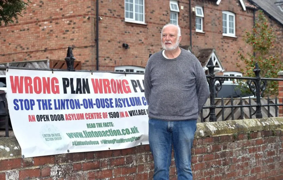 Local resident Phil Banks stands beside a banner reading "Wrong plan wrong place" in Linton-on-Ouse.