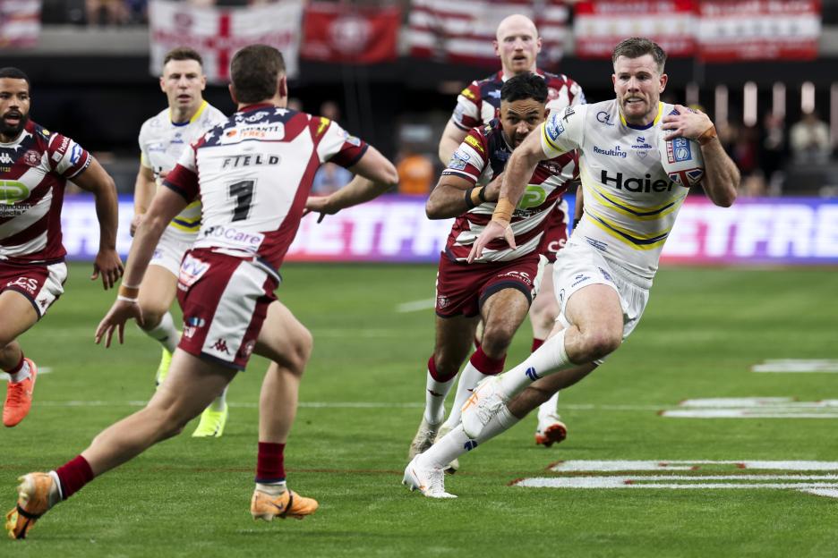 Rugby player running with the ball during a Wigan Warriors vs Warrington Wolves game.