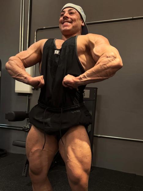 A male bodybuilder flexing his biceps in a gym.
