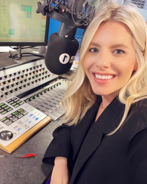 Mollie King posing with a BBC Radio 1 microphone and soundboard.