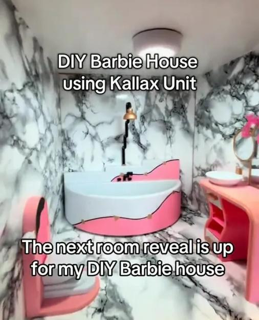 A DIY Barbie house bathroom with marble-patterned walls, a pink and white bathtub, a pink vanity with a mirror, and a pink toilet.