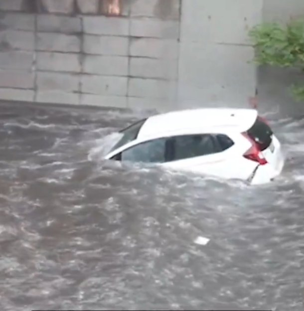 White car partially submerged in floodwaters.