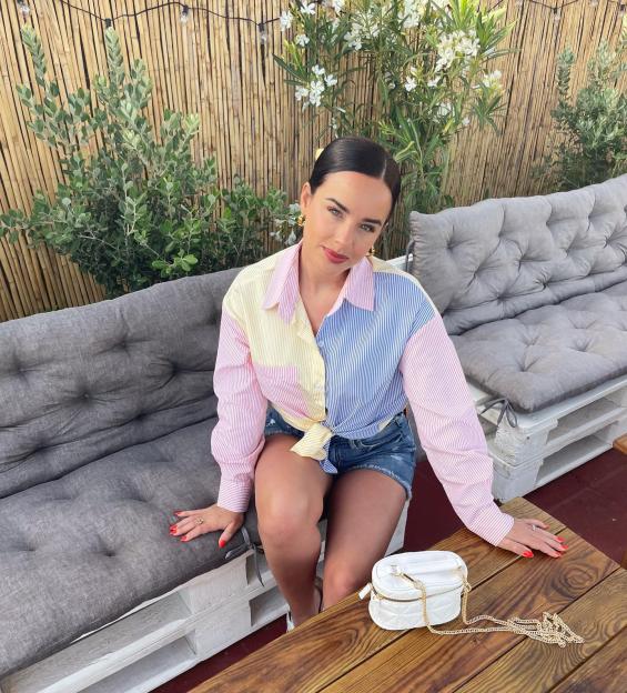 Georgia May Foote sitting on a patio bench with a color-blocked shirt.