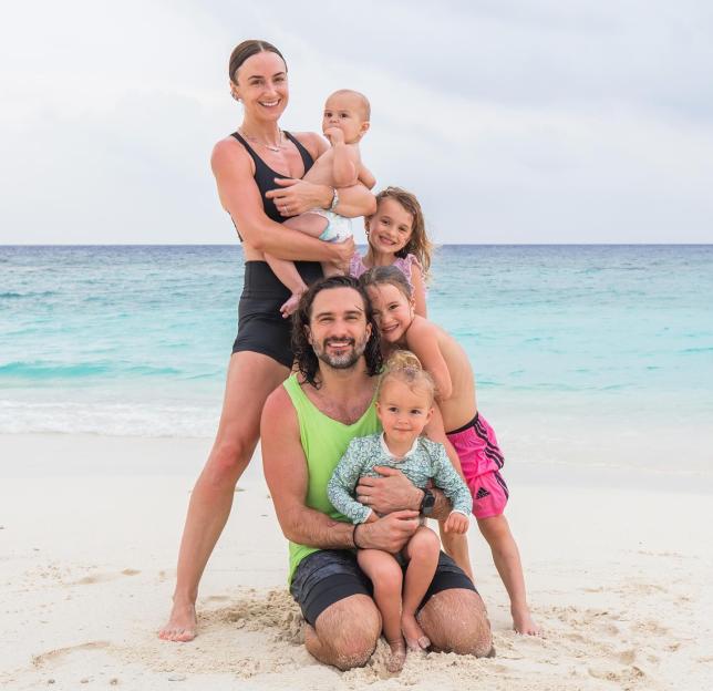 Family of six on a beach with turquoise water.