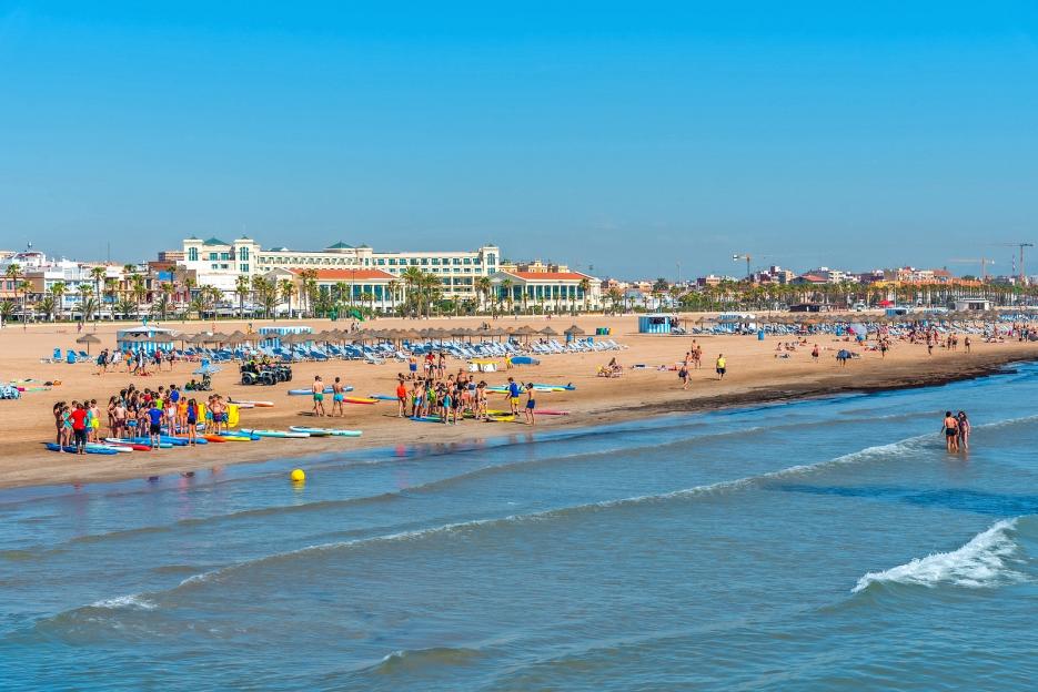 People enjoying a sunny day on Cabanyal beach in Valencia, Spain.
