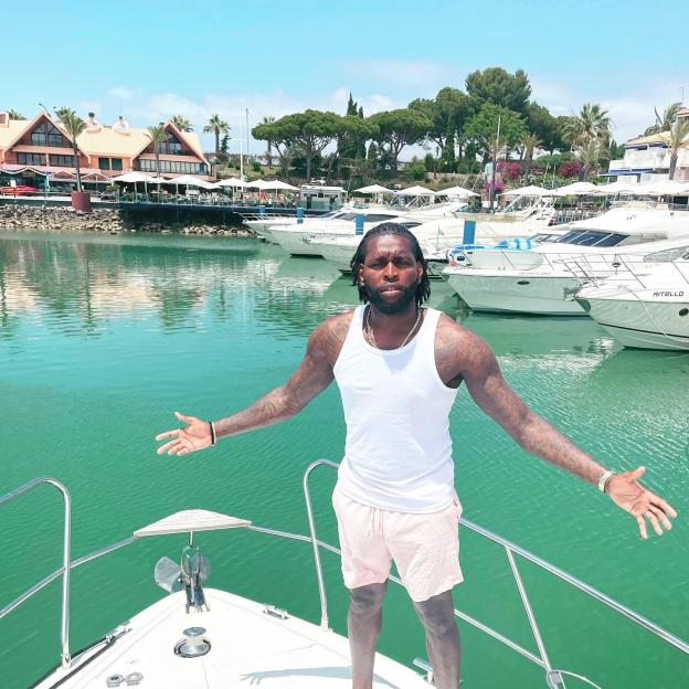 Jay Emmanuel-Thomas standing on a boat in a marina with his arms spread.
