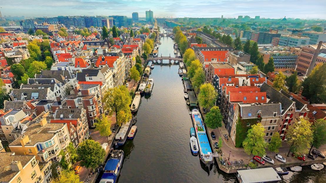 Aerial view of the Jordaan district in Amsterdam, featuring canals lined with houseboats and historic "gingerbread" houses.