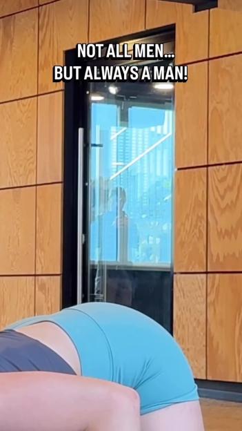 A man seen looking through a glass door at a woman stretching in a gym, with text that reads "NOT ALL MEN... BUT ALWAYS A MAN!"