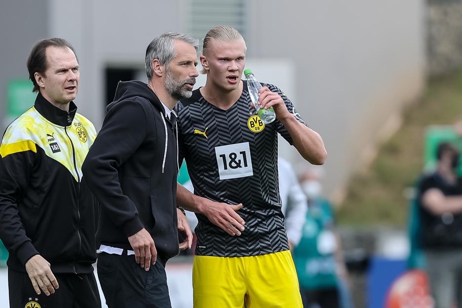 Borussia Dortmund head coach Marco Rose and player Erling Haaland discuss strategy during a Bundesliga match.