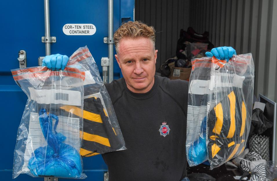 Det. Sgt. Rob O'Brien holding up two plastic evidence bags containing drugs.