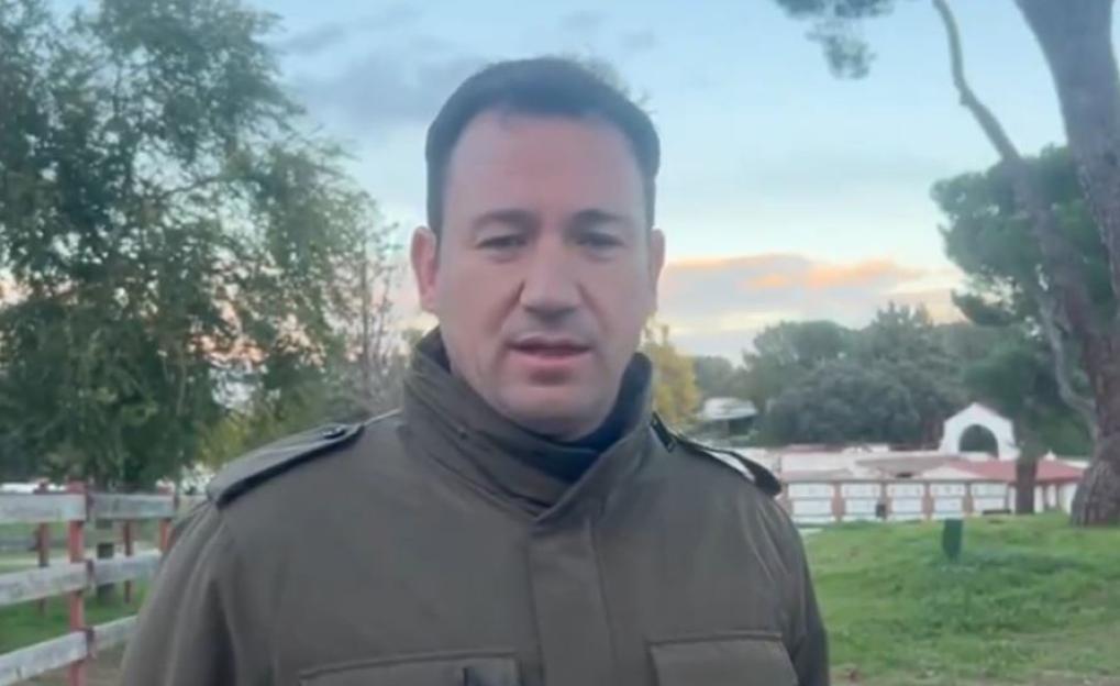 A man in a green jacket standing outdoors.