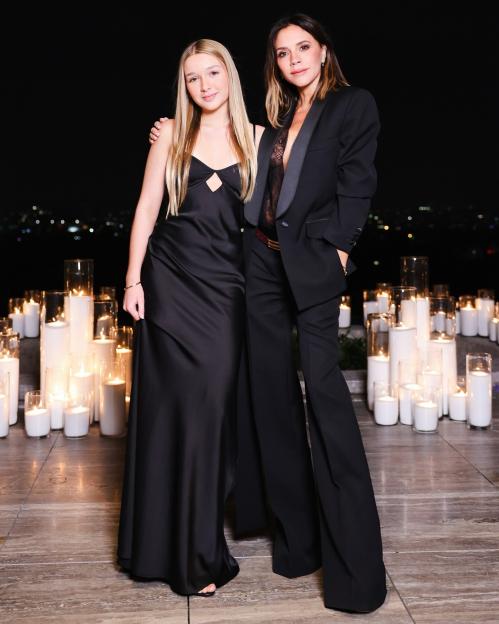 Victoria Beckham and Harper Beckham posing outdoors at night, surrounded by candles.