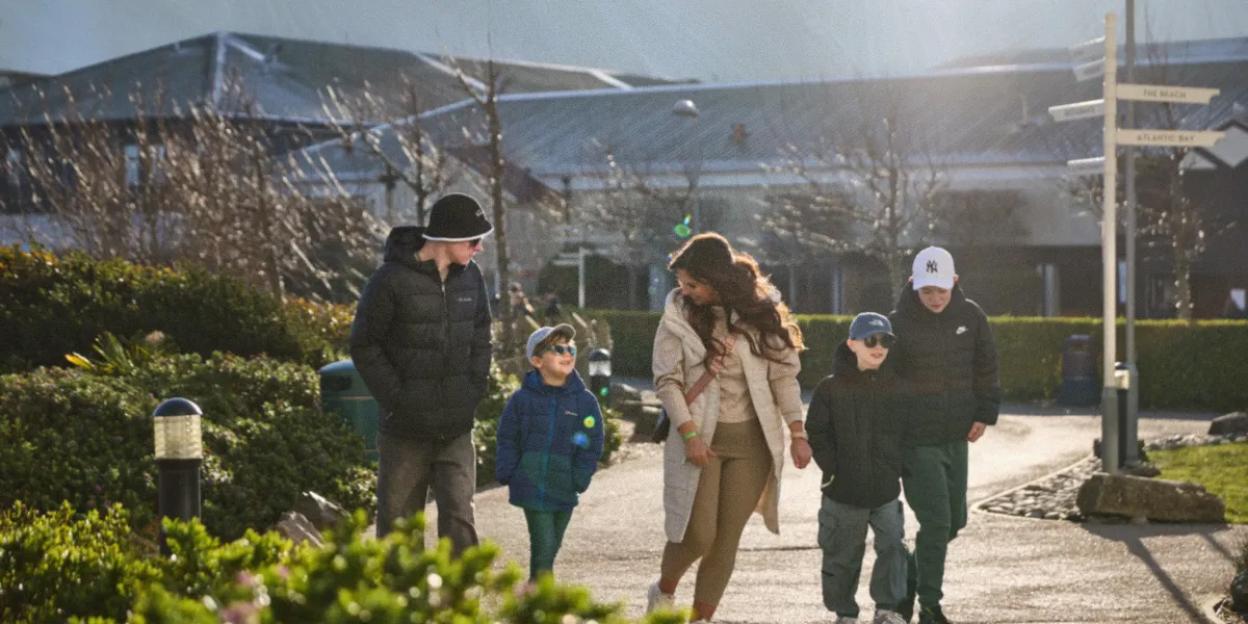 Family with three children walking on a sunny path.