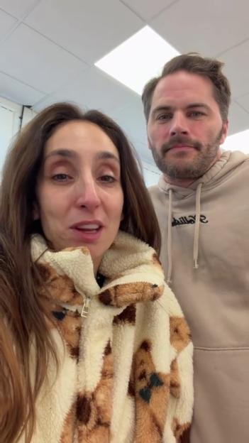 A woman wearing a teddy bear print jacket next to a man in a beige hoodie.