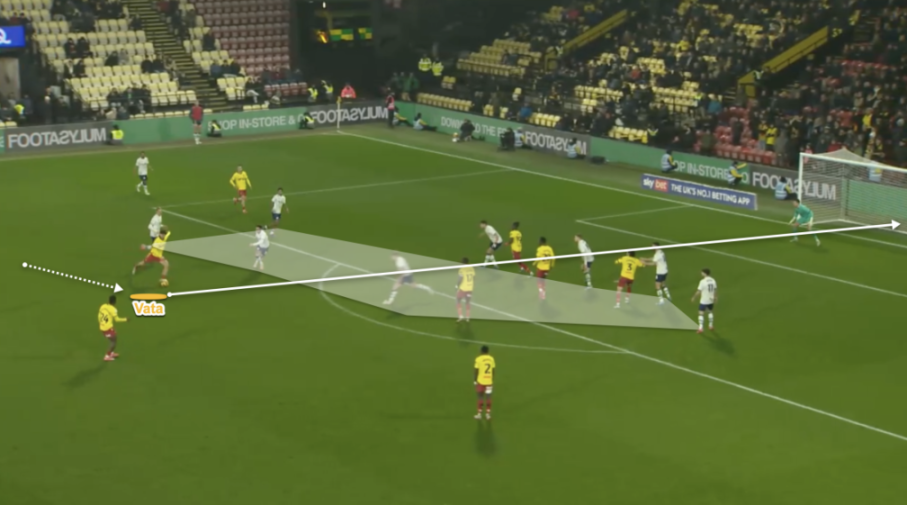 A soccer player in a yellow and red uniform passes the ball to a teammate near the goal.