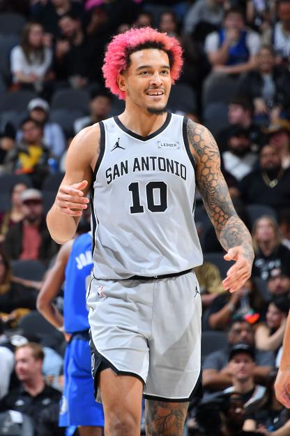 Jeremy Sochan #10 of the San Antonio Spurs, with pink hair and tattoos, smiles while playing against the Dallas Mavericks.