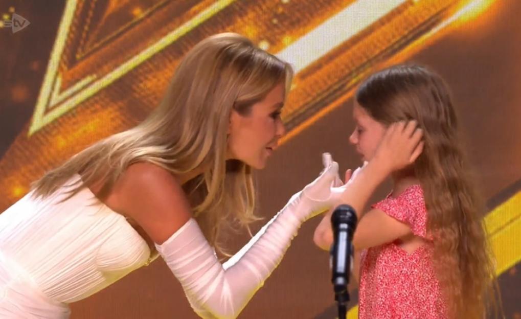 Amanda Holden comforting a young girl on stage.
