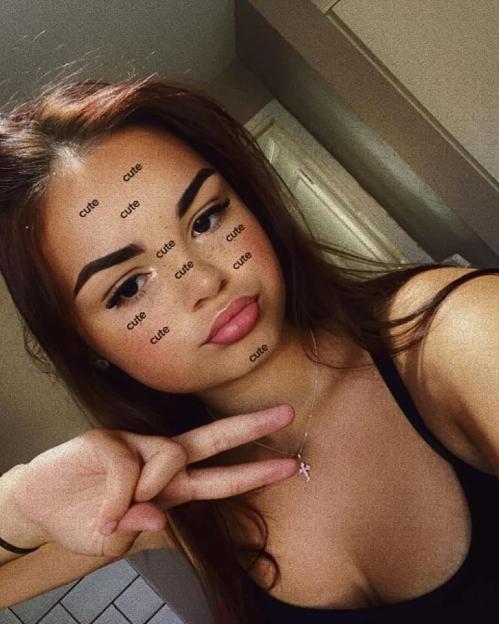 Rosie Hanson posing with a peace sign, with "cute" stickers on her face.