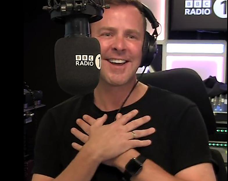 Scott Mills smiling and holding his hands to his chest during his final BBC Radio 1 show.