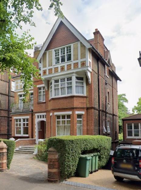 A large brick house with white trim, a bay window, and a gabled roof.