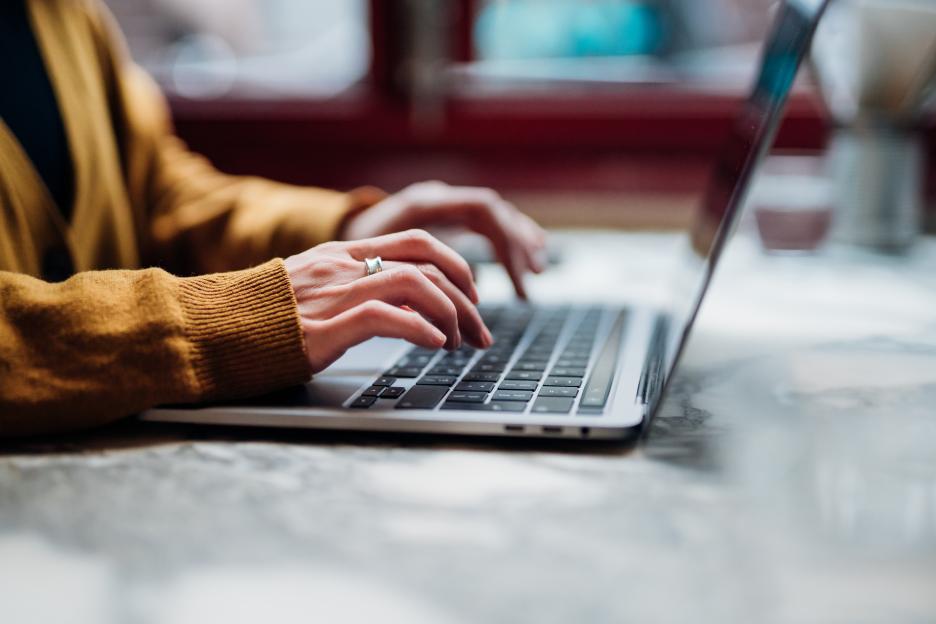 Side view of a female typing on a laptop keyboard.