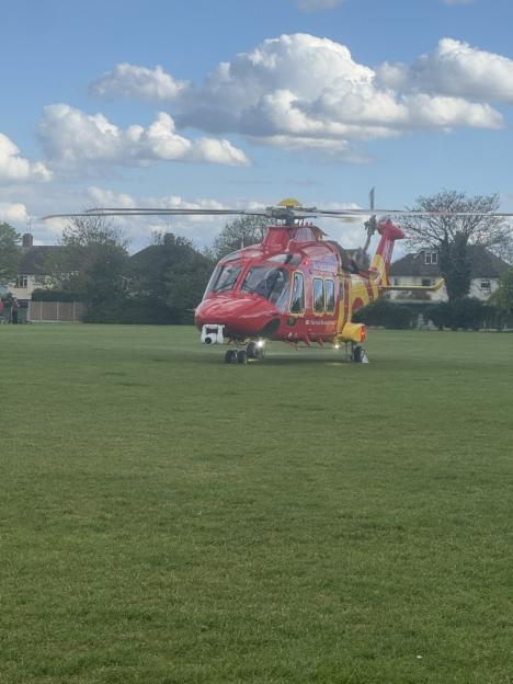 A red and yellow air ambulance helicopter on a grassy field.