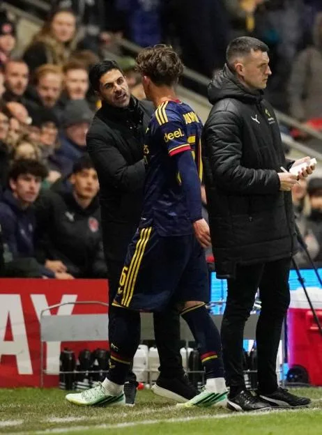 Arsenal manager Mikel Arteta speaks with player Max Dowman on the sideline during a match.