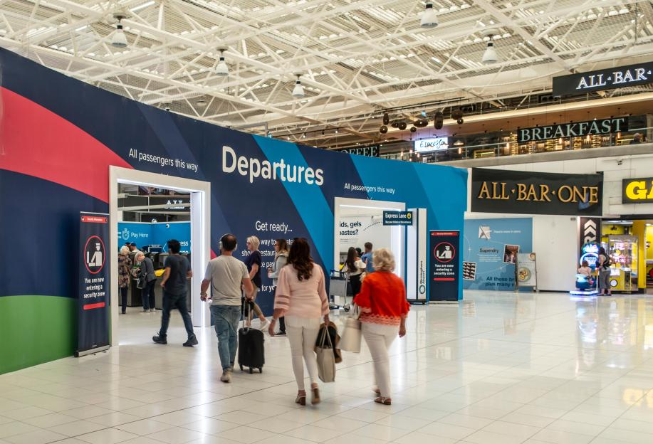 Passengers walking towards the Departures Area of Birmingham International Airport, England, UK. Sign for All Bar One restaurant.