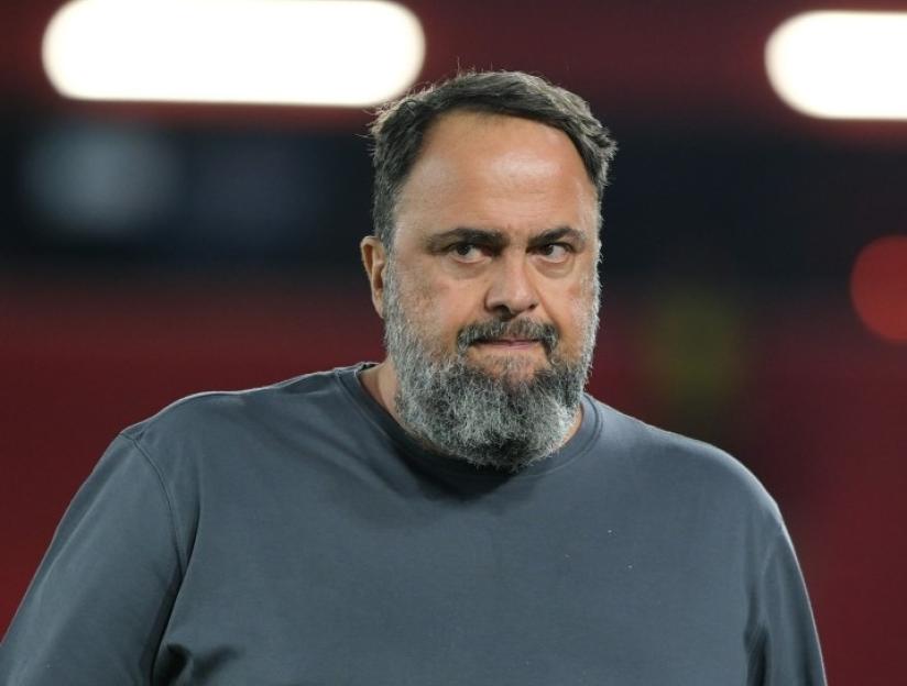 A man with a dark beard and gray shirt looks toward the right of the frame.