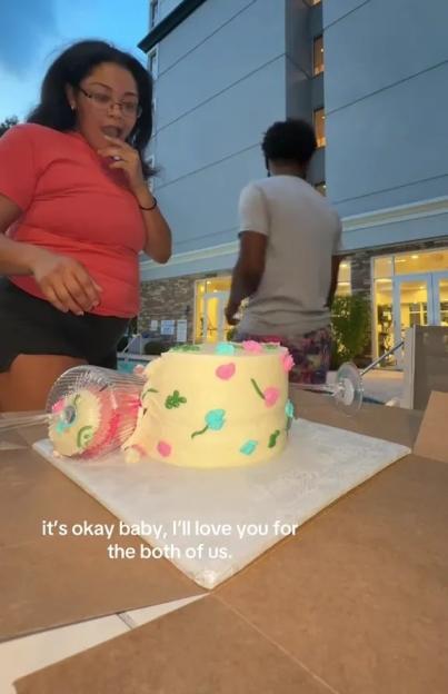 A woman looking shocked while a man walks away from a gender reveal cake.