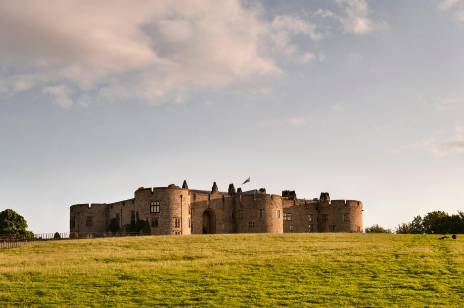 Chirk Castle in Wrexham, Wales, built by Roger Mortimer, from a distance across a field.