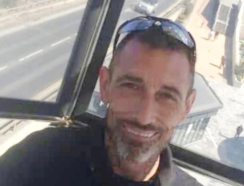 Adam Lucas smiling at the camera with sunglasses resting on his head.