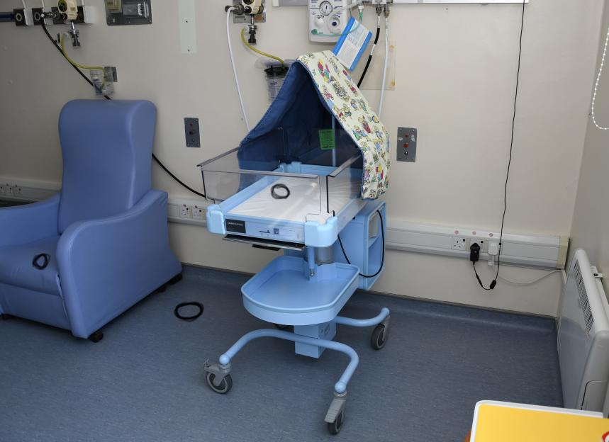 A cot with black circles indicating vomit stains, in a hospital room.