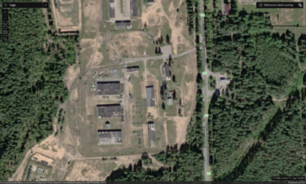 Satellite image of the Luga military base in Russia, showing several large buildings, infrastructure, and an adjacent highway.