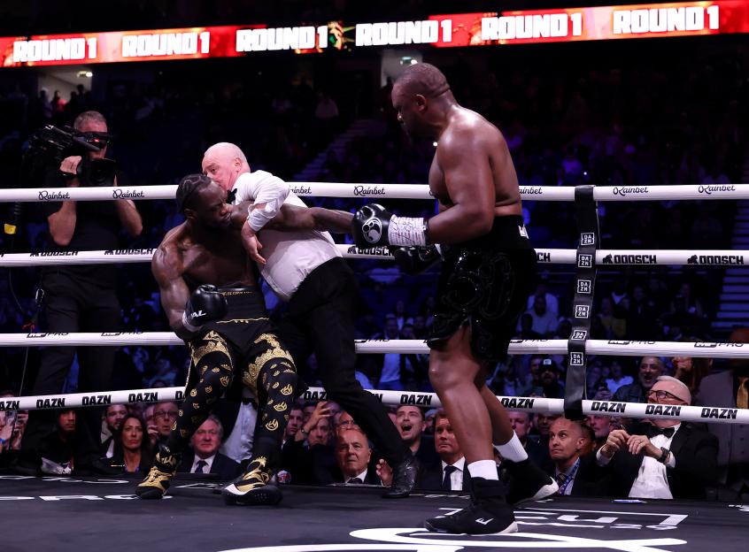 Referee Mark Bates attempts to pull apart Deontay Wilder and Derek Chisora during their heavyweight fight.
