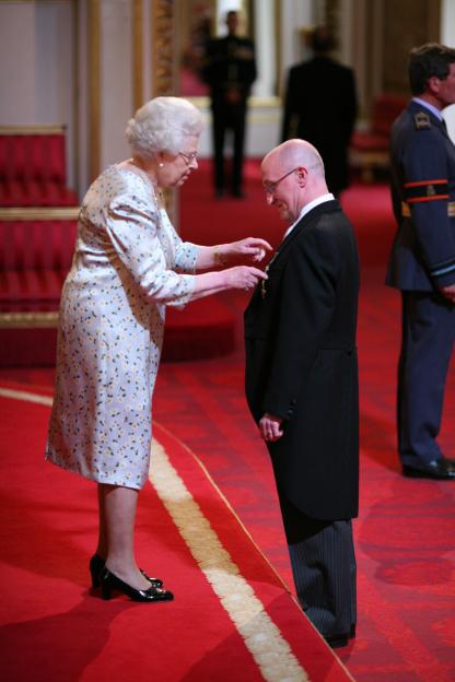 Queen Elizabeth II bestowing an OBE on Robert Cummines.