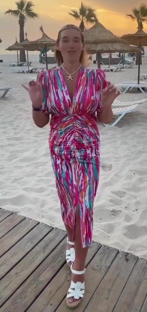 Becki Jones in a tight, colorful dress on a beach at sunset.